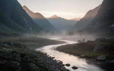 Eine friedliche Berglandschaft im Morgengrauen mit einem ruhig fließenden Fluss durch ein nebeliges Tal. - Foto: über boerse-global.de