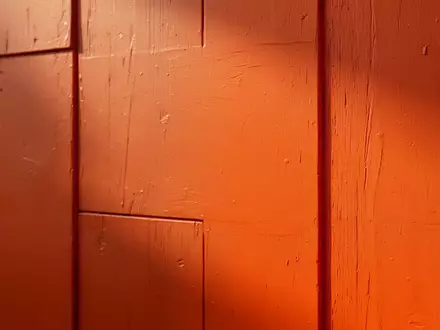 Eine glatte, leuchtend orangefarbene Wandfläche mit natürlichem Lichteinfall und feiner Oberflächenstruktur. - Foto: über boerse-global.de