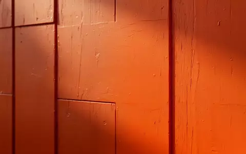 Eine glatte, leuchtend orangefarbene Wandfläche mit natürlichem Lichteinfall und feiner Oberflächenstruktur. - Foto: über boerse-global.de