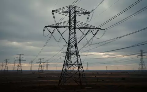 Hochspannungsmast einer Freileitung in einer weiten, flachen Landschaft unter bedecktem Himmel. - Foto: über boerse-global.de