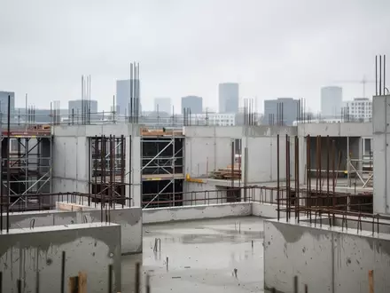 Eine unfertige Wohnimmobilien-Baustelle mit Betonstrukturen und Gerüsten unter bewölktem Himmel. - Foto: über boerse-global.de