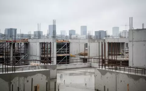 Eine unfertige Wohnimmobilien-Baustelle mit Betonstrukturen und Gerüsten unter bewölktem Himmel. - Foto: über boerse-global.de