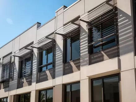 Moderne Gebäudefassade mit außenliegendem Sonnenschutz bei hellem Tageslicht - Foto: über boerse-global.de