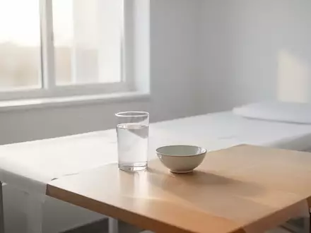 Ein heller, steriler Behandlungsraum mit einem Glas Wasser und einer leeren Schale auf einem Holztisch. - Foto: über boerse-global.de