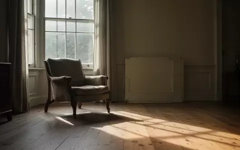 Ein ruhiges, sonnendurchflutetes Wohnzimmer mit einem leeren Sessel an einem Fenster, das sanftes Licht in den Raum wirft. - Foto: über boerse-global.de