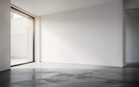 Ein minimalistischer, lichtdurchfluteter Raum mit poliertem Betonboden und einer leeren weißen Wand. - Foto: über boerse-global.de