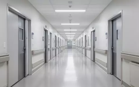 Ein langer, leerer Krankenhausflur mit glänzenden Böden und weißen Wänden in einer modernen Klinik. - Foto: über boerse-global.de