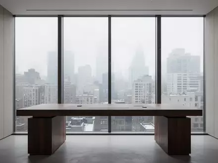 Ein minimalistischer, moderner Arbeitsplatz an einem großen Fenster mit Blick auf eine städtische Skyline bei Tageslicht. - Foto: über boerse-global.de