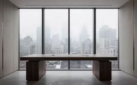 Ein minimalistischer, moderner Arbeitsplatz an einem großen Fenster mit Blick auf eine städtische Skyline bei Tageslicht. - Foto: über boerse-global.de