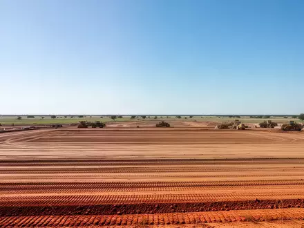 Eine weitläufige Baustelle in der texanischen Landschaft mit vorbereitetem Erdboden und Baugerät unter weitem Himmel. - Foto: über boerse-global.de