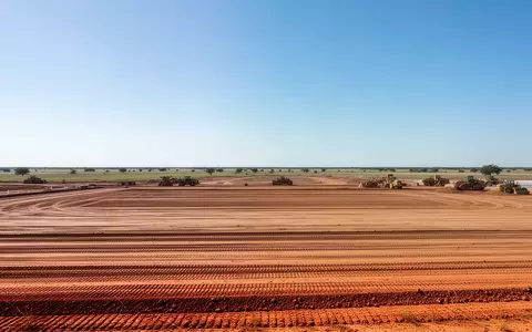 Eine weitläufige Baustelle in der texanischen Landschaft mit vorbereitetem Erdboden und Baugerät unter weitem Himmel. - Foto: über boerse-global.de