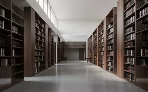 Ein moderner, minimalistischer Bibliotheksraum mit hohen Holzregalen und poliertem Betonboden in hellem Tageslicht. - Foto: über boerse-global.de