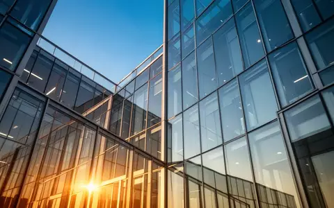 Moderne Glas- und Stahlfassade eines Bürogebäudes bei Sonnenlicht als Symbol für Investitionen und Wachstum. - Foto: über boerse-global.de