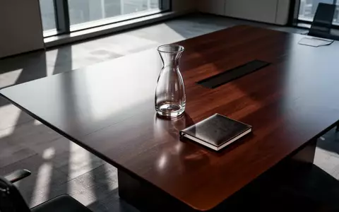 Ein leerer, minimalistischer Konferenztisch in einem modernen Büro mit natürlichem Lichteinfall. - Foto: über boerse-global.de