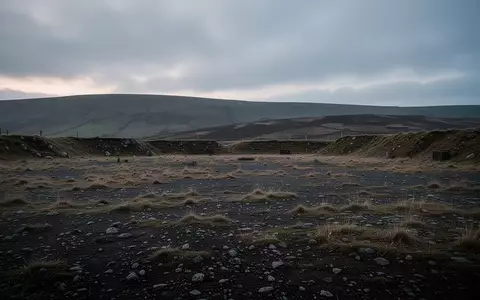 Eine weite, unebene Trainingsfläche in Wales bei Dämmerung, umgeben von sanften Hügeln unter einem bewölkten Himmel. - Foto: über boerse-global.de
