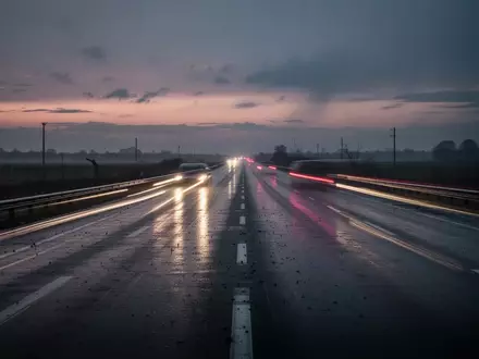 Eine menschenleere, regennasse Autobahn bei Dämmerung mit den Lichtspuren vorbeifahrender Autos. - Foto: über boerse-global.de