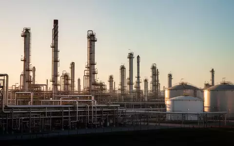 Ein weitläufiges Ölraffinerie-Gelände mit komplexen Rohrleitungssystemen und Destillationstürmen im warmen Licht der Abendsonne. - Foto: über boerse-global.de