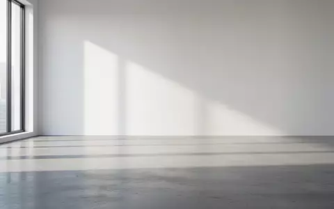 Ein minimalistischer, heller Büroraum mit klaren Linien und natürlichem Licht, das auf einen Betonboden fällt. - Foto: über boerse-global.de