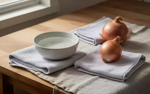 Ein minimalistischer Holztisch mit einer Schale Essig, einem Mikrofasertuch und einer Zwiebel zur Haushaltsreinigung. - Foto: über boerse-global.de