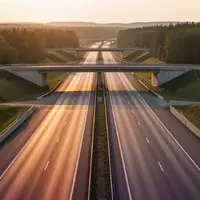 Weitläufiges Autobahnkreuz bei Sonnenuntergang mit weiten Fahrbahnen und grünen Böschungen ohne sichtbare Schilder oder Verkehr. - Foto: über boerse-global.de