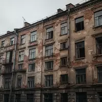 Fassade eines sanierungsbedürftigen Wohngebäudes in einem städtischen Umfeld bei bewölktem Himmel. - Foto: über boerse-global.de