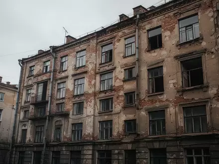 Fassade eines sanierungsbedürftigen Wohngebäudes in einem städtischen Umfeld bei bewölktem Himmel. - Foto: über boerse-global.de