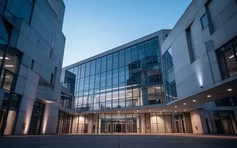 Modernes Verwaltungsgebäude in der Abenddämmerung mit klarer Architektur und dezenter Beleuchtung. - Foto: über boerse-global.de