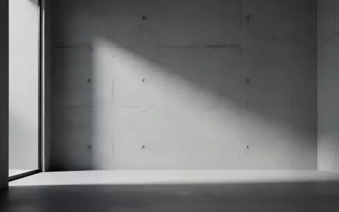 Ein minimalistischer, leerer Raum mit sanftem, diffusem Licht und Schattenwurf an einer Betonwand, der eine technische Störung symbolisiert. - Foto: über boerse-global.de