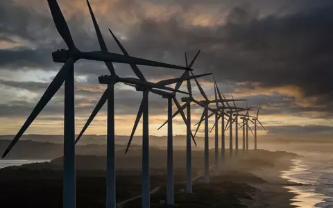 Große Windkraftanlagen in einer weitläufigen Landschaft bei Dämmerung. - Foto: über boerse-global.de
