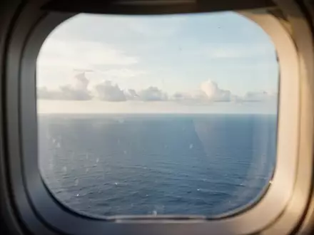 Blick aus einem Flugzeugfenster auf den ruhigen Horizont über dem Meer bei natürlichem Tageslicht. - Foto: über boerse-global.de