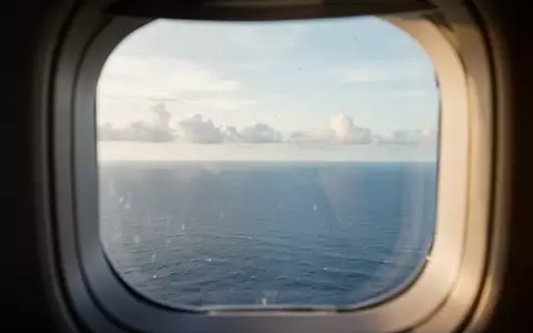 Blick aus einem Flugzeugfenster auf den ruhigen Horizont über dem Meer bei natürlichem Tageslicht. - Foto: über boerse-global.de