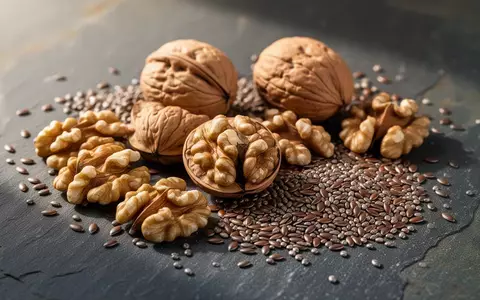 Nahaufnahme von Walnüssen, Leinsamen und Chiasamen auf einer dunklen Steinoberfläche als natürliche Omega-3-Quellen. - Foto: über boerse-global.de