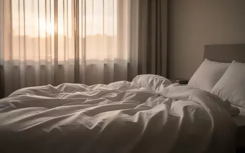 Ein ungemachtes Bett in einem ruhigen Schlafzimmer im sanften Morgenlicht, das eine Atmosphäre der Erholung vermittelt. - Foto: über boerse-global.de