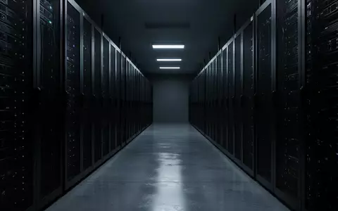 Ein düsterer, moderner Serverraum mit dunklen Serverschränken in einer langen Flucht, beleuchtet durch kühles Umgebungslicht. - Foto: über boerse-global.de