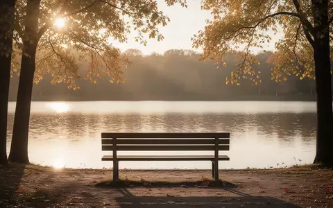 Eine leere Parkbank vor einem ruhigen See im goldenen Abendlicht. - Foto: über boerse-global.de