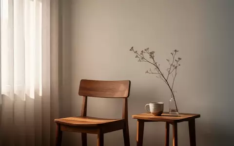 Ein minimalistischer, lichtdurchfluteter Raum mit einem leeren Holzstuhl und einer schlichten Vase auf einem Beistelltisch. - Foto: über boerse-global.de
