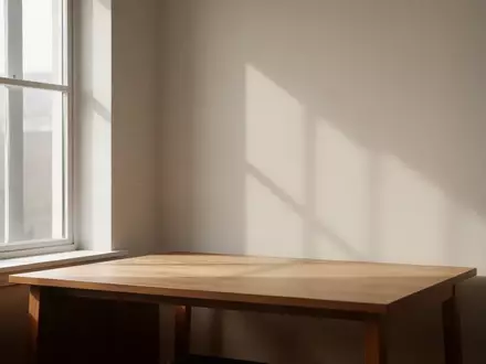 Ein minimalistischer, aufgeräumter Arbeitsplatz mit weichem Tageslicht, das durch ein Fenster auf eine leere Wand fällt. - Foto: über boerse-global.de
