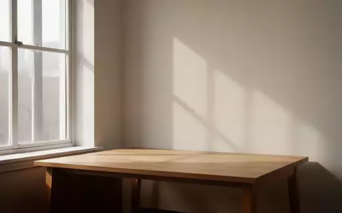 Ein minimalistischer, aufgeräumter Arbeitsplatz mit weichem Tageslicht, das durch ein Fenster auf eine leere Wand fällt. - Foto: über boerse-global.de