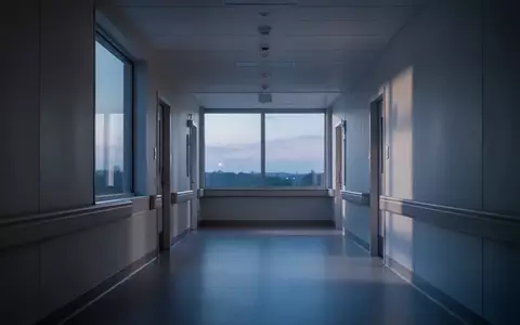 Ein ruhiger, leerer Krankenhausflur bei Dämmerung mit sanftem Lichteinfall durch ein großes Fenster. - Foto: über boerse-global.de