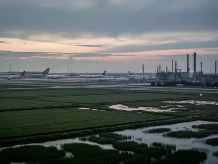 Eine weitläufige Grünfläche nahe einer Flughafeninfrastruktur bei Dämmerung. - Foto: über boerse-global.de