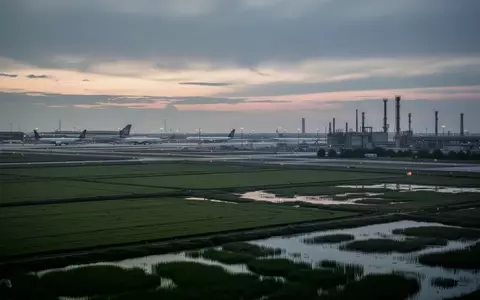 Eine weitläufige Grünfläche nahe einer Flughafeninfrastruktur bei Dämmerung. - Foto: über boerse-global.de