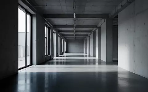 Ein leerer, moderner Industrieflur mit Betonboden und einfallendem Tageslicht, der eine angespannte Arbeitsatmosphäre symbolisiert. - Foto: über boerse-global.de