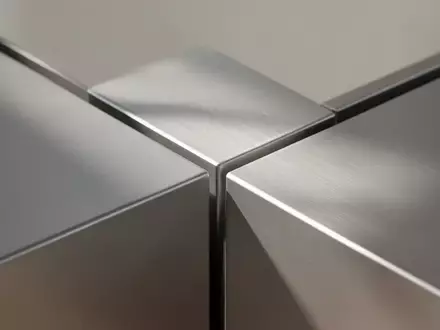 Eine Nahaufnahme einer modernen, gebürsteten Aluminiumoberfläche mit minimalistischen geometrischen Linien und weichem Tageslicht. - Foto: über boerse-global.de