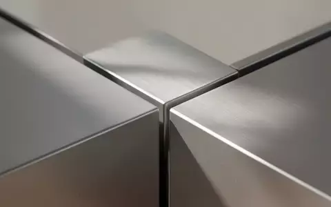 Eine Nahaufnahme einer modernen, gebürsteten Aluminiumoberfläche mit minimalistischen geometrischen Linien und weichem Tageslicht. - Foto: über boerse-global.de