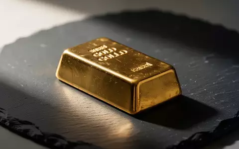 Ein einzelner Goldbarren auf einer dunklen, texturierten Schieferoberfläche bei natürlichem Seitenlicht. - Foto: über boerse-global.de