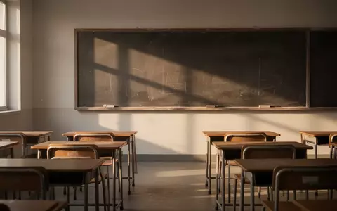 Ein leerer, sonnendurchfluteter Klassenraum mit leeren Schulbänken und einer unbeschriebenen Tafel. - Foto: über boerse-global.de
