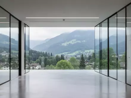 Ein modernes, minimalistisches Bürogebäude in Zürich mit Blick auf eine grüne Berglandschaft bei natürlichem Tageslicht. - Foto: über boerse-global.de
