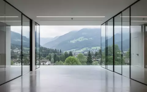 Ein modernes, minimalistisches Bürogebäude in Zürich mit Blick auf eine grüne Berglandschaft bei natürlichem Tageslicht. - Foto: über boerse-global.de