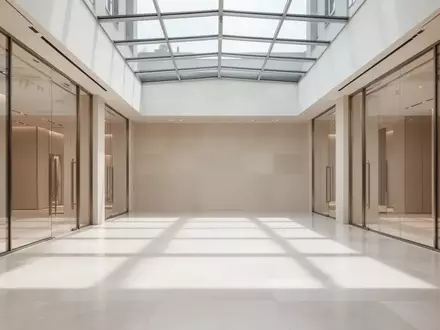 Ein minimalistischer, leerer Verkaufsraum mit poliertem Steinboden und hellem Tageslicht, das durch ein Glasdach fällt. - Foto: über boerse-global.de