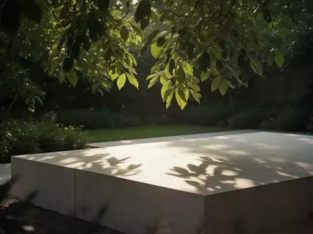 Sonnenlicht fällt durch grüne Blätter auf eine minimalistische Steinfläche in einem ruhigen Garten. - Foto: über boerse-global.de